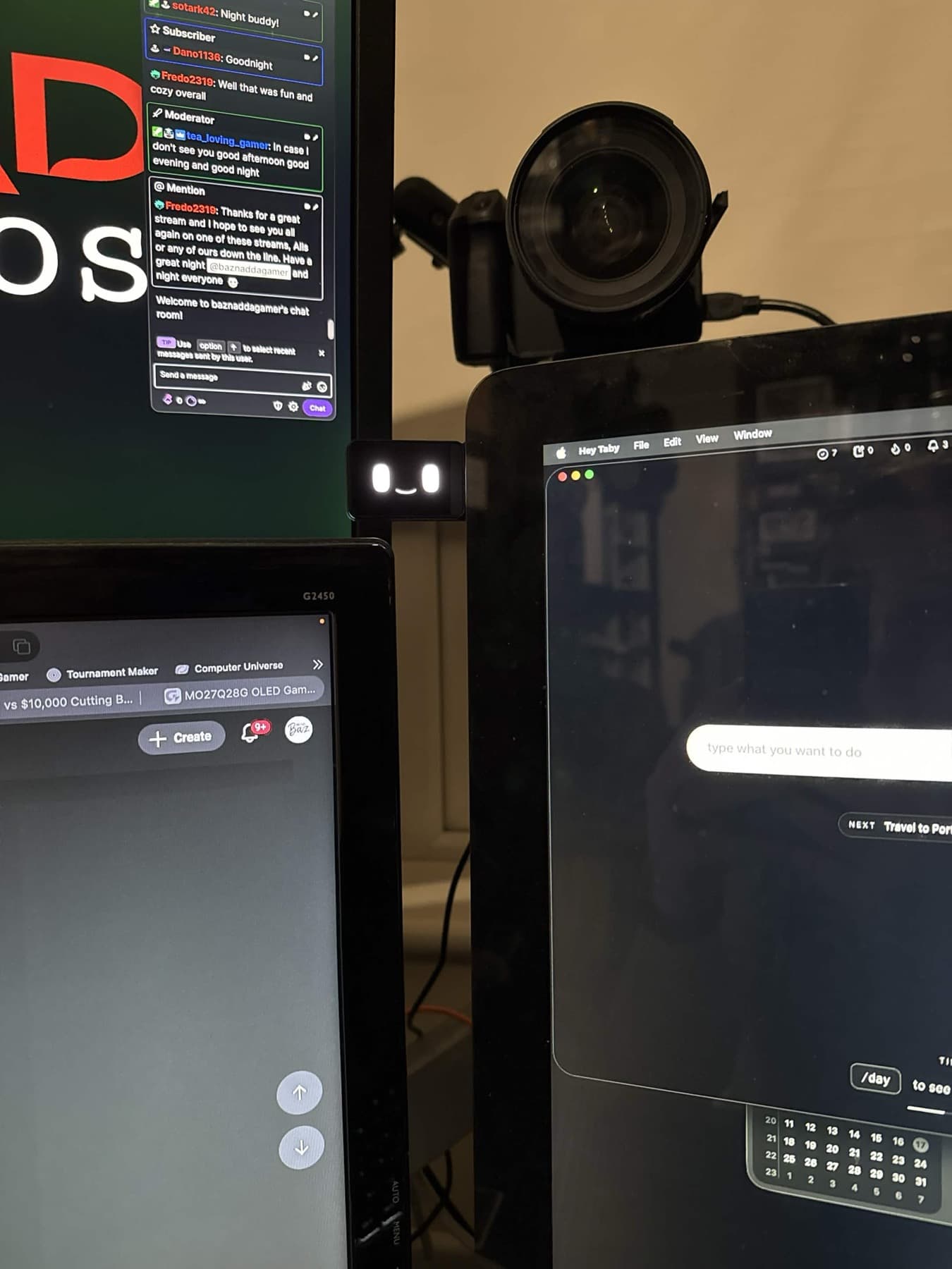 Taby mounted between screens in a darker desk setup.